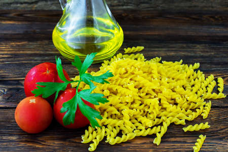 Macaroni, tomatoes on a wooden background.の写真素材