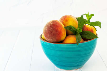 Peaches in a bowl. White background.の写真素材