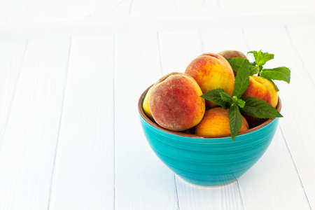 Peaches in a bowl. White background.の写真素材