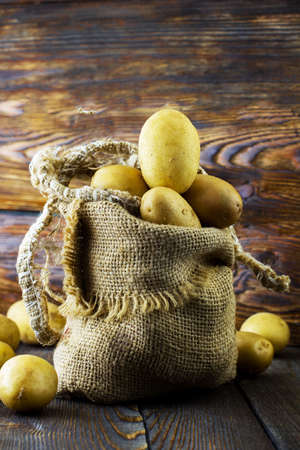 Potatoes in a bag. Wooden background.の写真素材