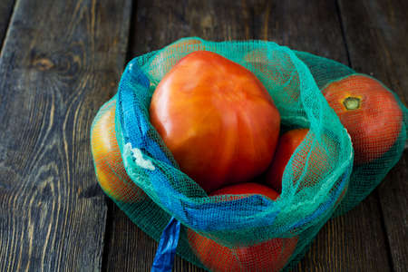 Tomatoes in a bag. Wooden background.の写真素材