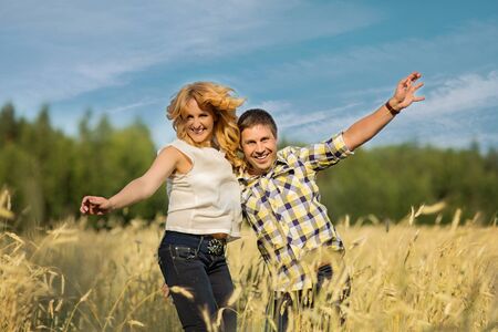 Happy couple jumping in rye field on sunny summer dayの写真素材