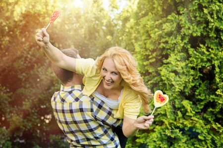 Happy woman in her husband's arms holding heart shaped lollipopsの写真素材