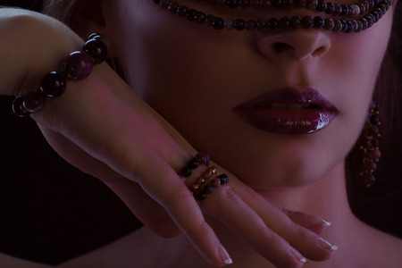 Half-face portrait of beautiful young girl in dark red bijouの写真素材