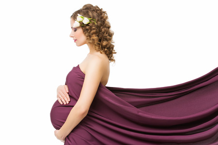 Beautiful pregnant young woman covered in purple fabric standing in profileの写真素材