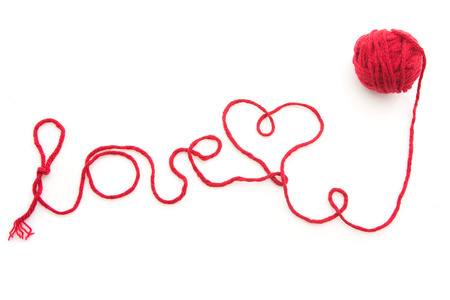 Word love written with red wool thread isolated over white backgroundの写真素材