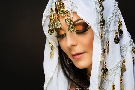 Closeup of beautiful young woman with oriental make-up and shawl over her headの写真素材