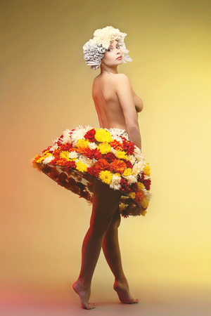 Beautiful naked young woman in headband and skirt decorated with flowersの写真素材