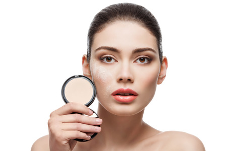 Beautiful young woman holding conrainer with pressed powder next to her face. Isolated over white...