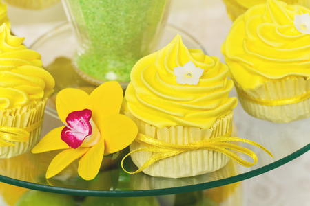 Close up of yellow cupcakes lying on transparent plate with flowerの写真素材