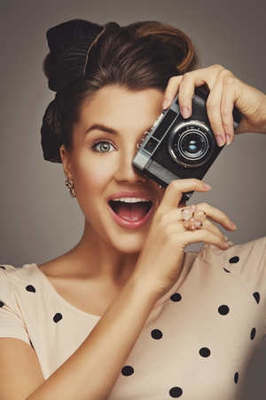 Beautiful young woman with retro photo camera. Surprised expression. Closeup portrait.の写真素材