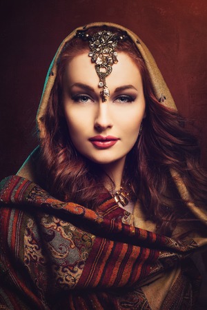 Beautiful young woman with bright makeup and shawl on head. Closeup portrait.の写真素材