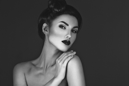 Beautiful young woman with dark red lips and hairdo. Beauty shot. Over grey background. Copy space.の写真素材