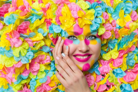 Closeup of young woman face in colorful flower petals. Beauty shot. Face paint.の写真素材
