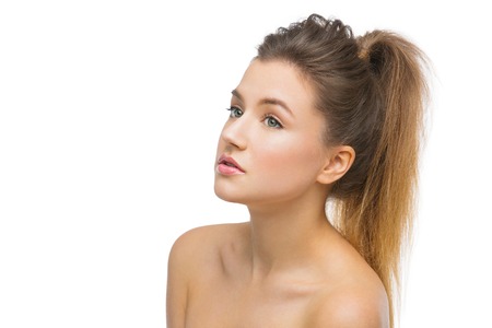 Beautiful young woman with soft skin and hair in ponytail. Beauty shot. Isolated over white background. Copy space.の写真素材