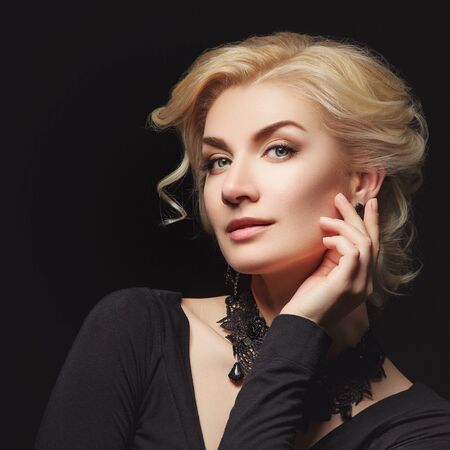 Beautiful blond young woman with natural makeup and stylish hairdo over dark grey background. Copy space.の写真素材