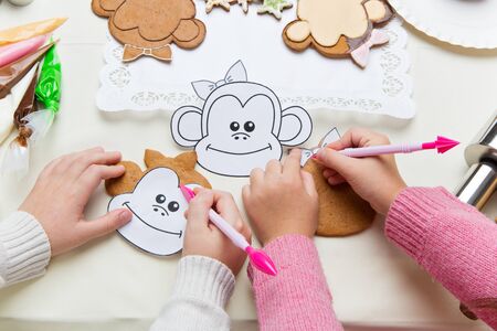 Children hands making gingerbread cookies with monkey head paper shapeの写真素材