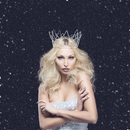 Beautiful young woman in crown and silver top over black background. Winter queen. Copy space.の写真素材