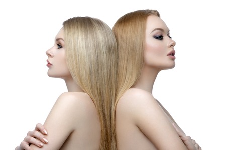 Two beautiful girls with long blond straight hair and bright makeup. Isolated over white background. Closeup studio beauty shot.の写真素材