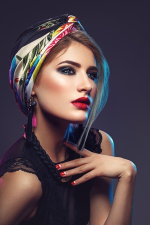 Beautiful girl with bright make-up and shawl on headの写真素材