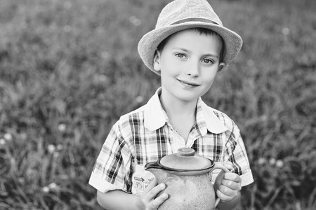 handsome little boy standing in hat with jugの写真素材