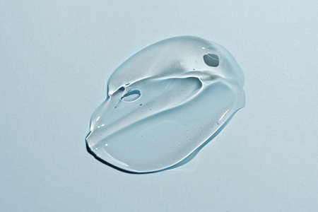 Liquid gel smear isolated on blue background. Beauty cosmetic smudge such as pure transparent aloe lotion, facial jelly serum, cleanser, shower gel or shampoo top viewの写真素材