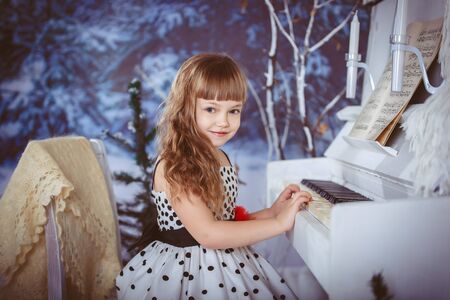 little girl playing piano Christmas in the winter forestの写真素材