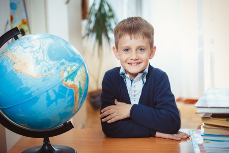 The schoolboy sits right at his desk and is ready to learn