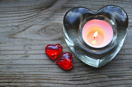 Heart shaped candle holder with burning candle and two decorative red hearts.Saint Valentine's Day or love concept.Selective focus.の写真素材
