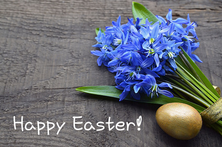 Happy Easter.Bouquet of first spring flowers and golden easter egg on old wooden...
