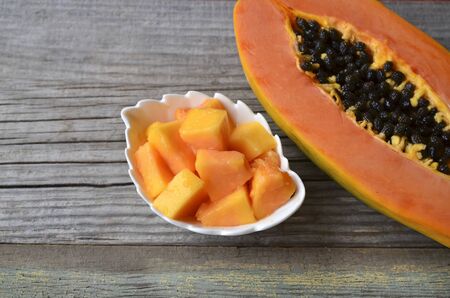 Fresh ripe organic papaya tropical fruit cut in half on old wooden background. Healthy eating, diet or vegan food concept. Selective focus.の写真素材