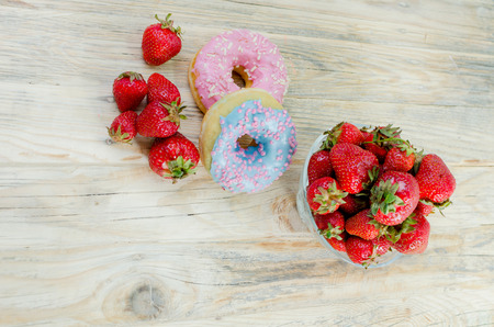 Strawberries on the table. Red strawberries on a wooden table in a glass vase. chocolate and soft buns.の写真素材