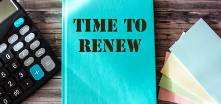 Time to update is written on a turquoise album, next to stickers and a calculator on a wooden backgroundの写真素材