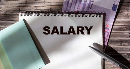 Salary text on notepad, pen, stickers and euro banknotes on wooden tableの写真素材