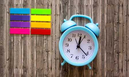 Clock and color stickers on wooden background