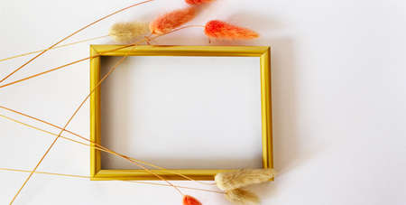 Layout with a gold border and dry flowers on a white background. Layout of the top view. Blog templateの写真素材