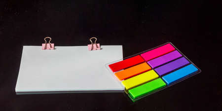 Blank blue sticker and colored stickers isolated on black glass background.