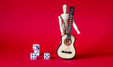 on a red background a wooden man with a guitar near diceの写真素材