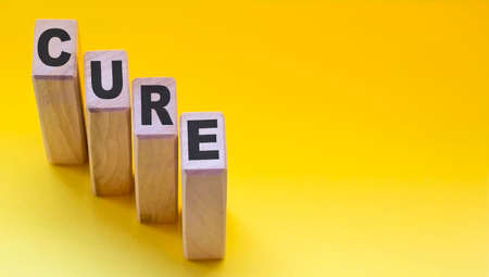 CURE - text on wooden blocks, medical concept, yellow backgroundの写真素材