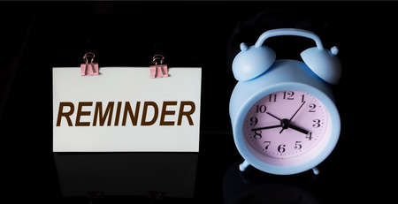 Reminder, text on sticker. There is an alarm clock on a black background