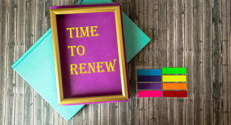Frame with inscription Time to renew and bright notepads and stickers on wooden table, business conceptの写真素材