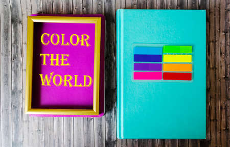 Text Color the world on a colorful notebook in a frame, next to a colored notebook and colorful stickers on a wooden tableの写真素材