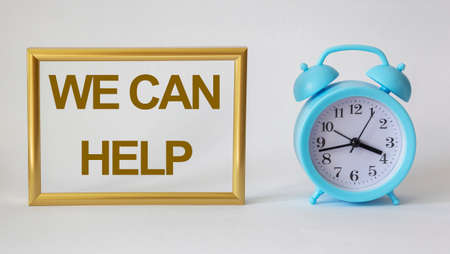 We can help, text in a gold frame on a white background, near a blue alarm clockの写真素材