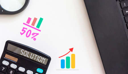 On the calculator, the inscription Solution, next to a white table is a magnifying glass, a laptop and graphsの写真素材