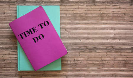 Quote on a notebook for inspiration: Time to do. Colored notepads lie on a wooden table
