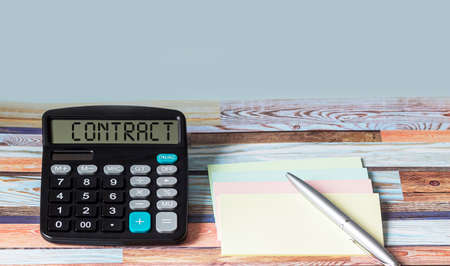 Contract, text on calculator and wooden background with stickers and pen. There is a place to writeの写真素材