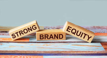 Wooden blocks with the text STRONG CAPITAL BRAND on a colored wooden background. Place to write