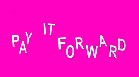 Phrase Pay It Forward made from wooden letters on a crimson background.の写真素材