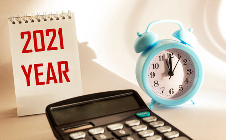 On a white background calendar with the text 2021 year, next to an alarm clock and a calculatorの写真素材