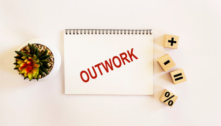 OUTWORK, the text is written on a notebook and a white background. On the table are wooden cubes with signs and there is a cactus flowerの写真素材